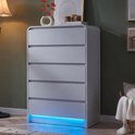 Grijze commode met 5 lades, afgeronde hoeken, RGB LED-verlichting aan de onderkant, decoratie met vaas, boeken en lamp.