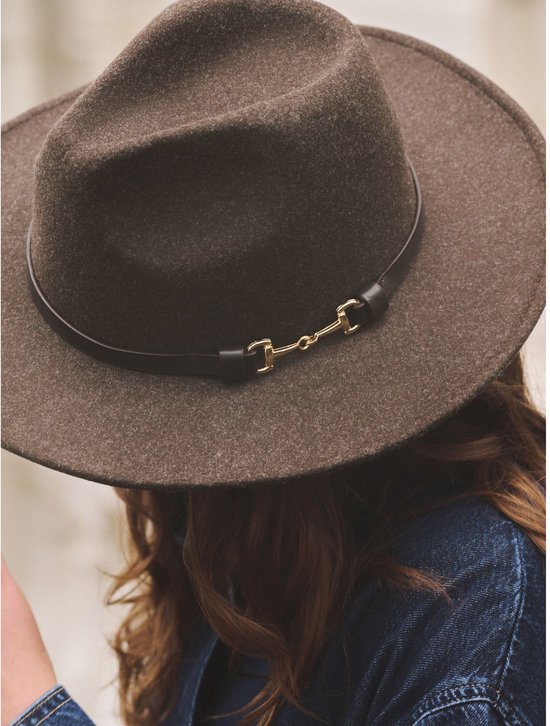 Bruine vilten fedora met zwarte band en gouden bitdetail, gedragen door een model.