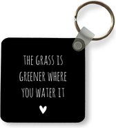 Sleutelhanger - Uitdeelcadeautjes - Engelse quote The grass is greener where you water it met een hartje tegen een zwarte achtergrond - Plastic
