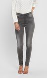 Model draagt een grijze skinny jeans met een witte geborduurde blouse.