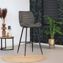 Antracietkleurige barkruk met horizontale stiksels, zittend op een jute mat in een tropisch interieur.