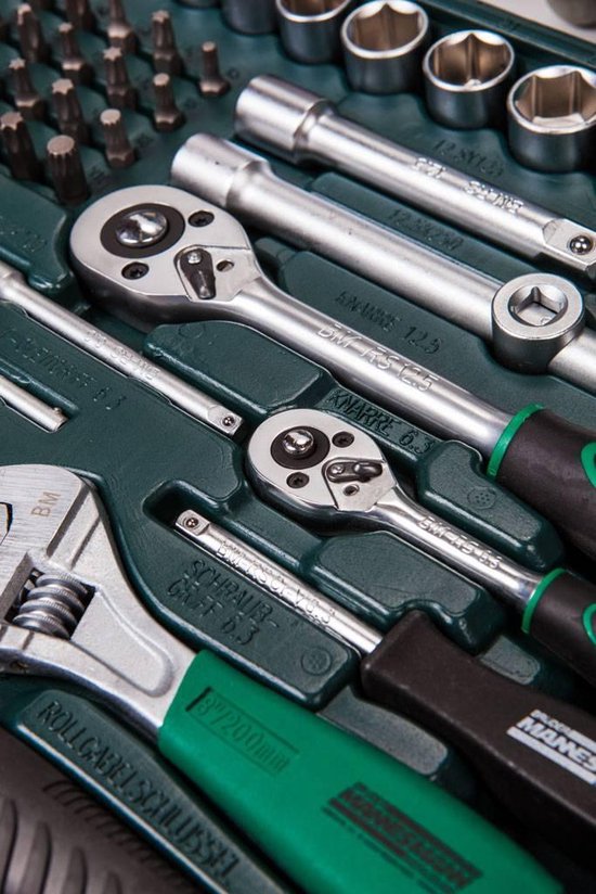 Close-up van ratelsleutels, een moersleutel en een schroevendraaier met groene handvatten in een gereedschapskoffer.
