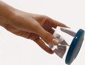 Hand houdt een transparante beker met blauw deksel vast.