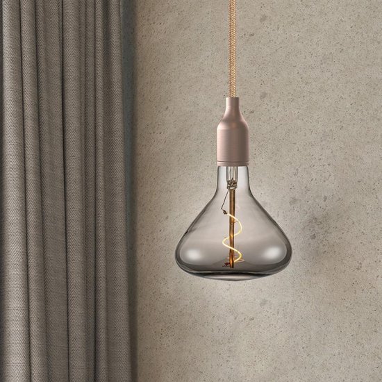 Een rookkleurige LED gloeilamp met spiraalfilament en koperkleurige fitting hangt voor een gordijn.