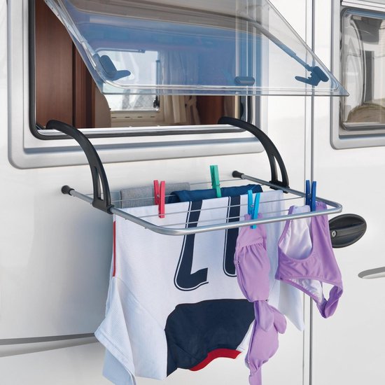 Zilverkleurig droogrek met zwarte ophangarmen, bevestigd aan een camper, met wasgoed.