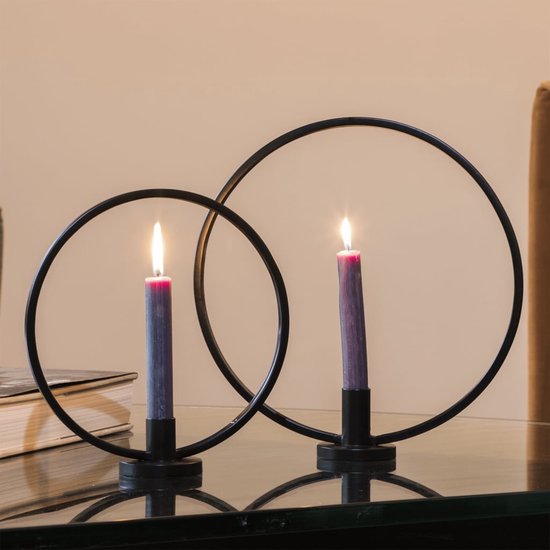 Twee zwarte ringkandelaren met paarse kaarsen, op een glazen tafel.