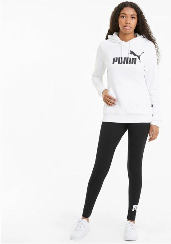 Model in een witte PUMA hoodie en zwarte PUMA-leggings, met logo op de linker enkel.