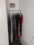 Een kledingroede met meerdere jurken, waaronder zwart, wit en rood met bloemenprint.