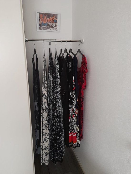 Een kledingroede met meerdere jurken, waaronder zwart, wit en rood met bloemenprint.