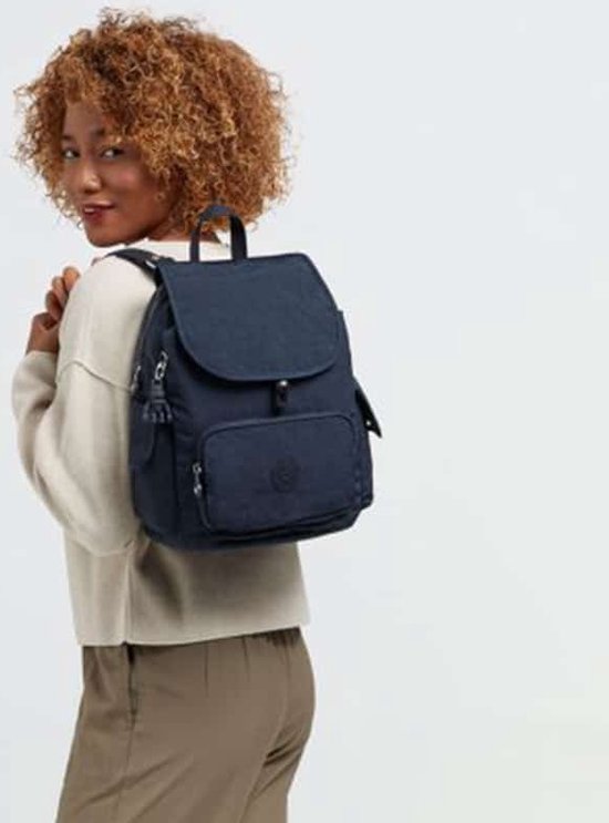 Vrouw met krullend haar draagt een donkerblauwe Kipling rugzak.