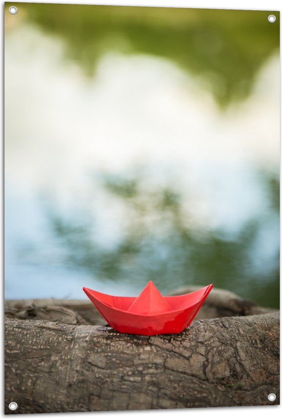 Tuinposter – Rood Origami Bootje op Boomstam langs Water - 70x105 cm Foto op Tuinposter (wanddecoratie voor buiten en binnen)