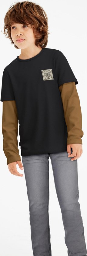 Jongetje in een zwarte longsleeve met bruine mouwen en grijze jeans.