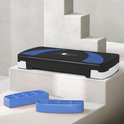 Zwarte aerobic step met blauwe accenten, staand op witte trappen.