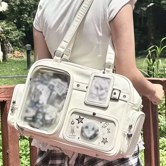 Off-white tas met transparante vakken, sterrenprint en ritssluitingen. Een hanger met een transparant venster aan de zijkant.