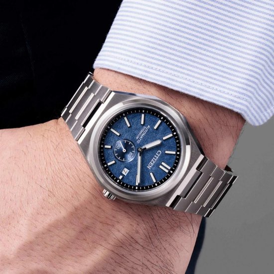 Zilverkleurig Citizen horloge met blauwe wijzerplaat met textuur gedragen om pols.