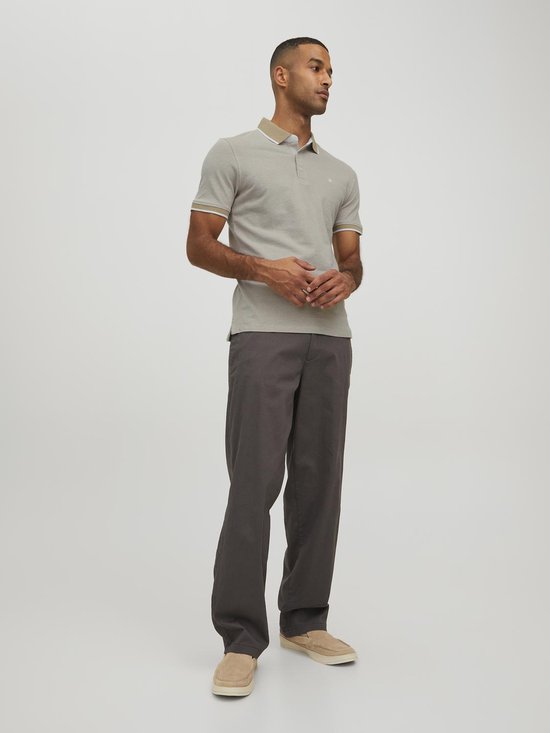 Man draagt een lichtgrijs poloshirt met beige kraag en manchetten met witte bies.