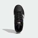Bovenaanzicht van een zwarte damessneaker met witte Adidas-strepen, gouden details en dikke zool.