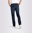 Donkerblauwe jeans gedragen door een man, gezien vanaf de achterkant. De jeans heeft oranje stiksels en een bruin label op de achterkant.