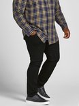 Man in een geruite blouse en zwarte jeans, hand in de zak.