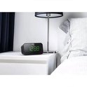 Zwarte Philips wekkerradio met groene digitale cijfers, op een nachtkastje.