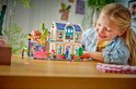Meisje speelt met LEGO Friends Liann's Familiehuis, met roze dak en blauwe ramen.