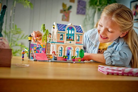 Meisje speelt met LEGO Friends Liann's Familiehuis, met roze dak en blauwe ramen.