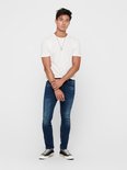 Man met witte gestreepte T-shirt en donkerblauwe skinny jeans. Draagt zwarte sneakers.