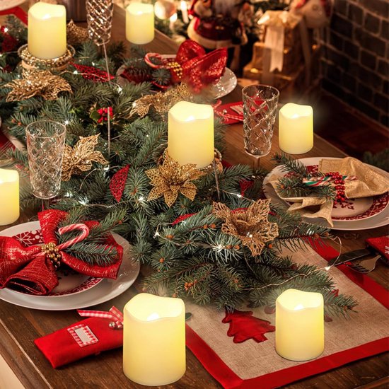 Een kersttafel gedecoreerd met dennentakken, rode strikken, gouden bladeren en witte LED-kaarsen met warme, flakkerende vlammen.