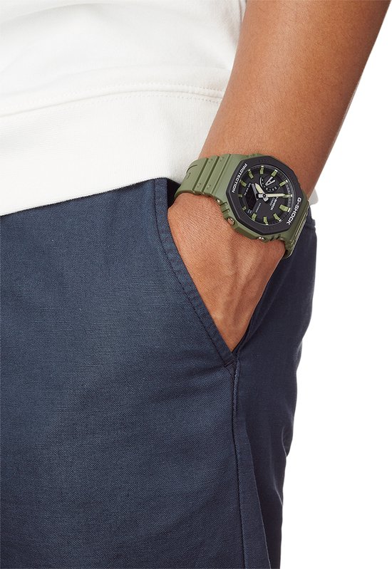 Groen G-Shock horloge met zwarte wijzerplaat op pols.