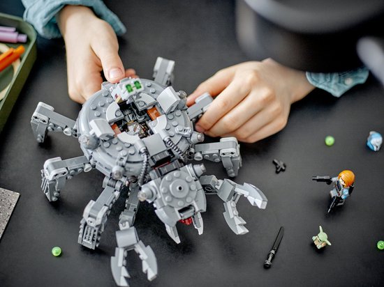LEGO Star Wars Spider Tank op een tafel, met kinderhanden die ermee spelen. 