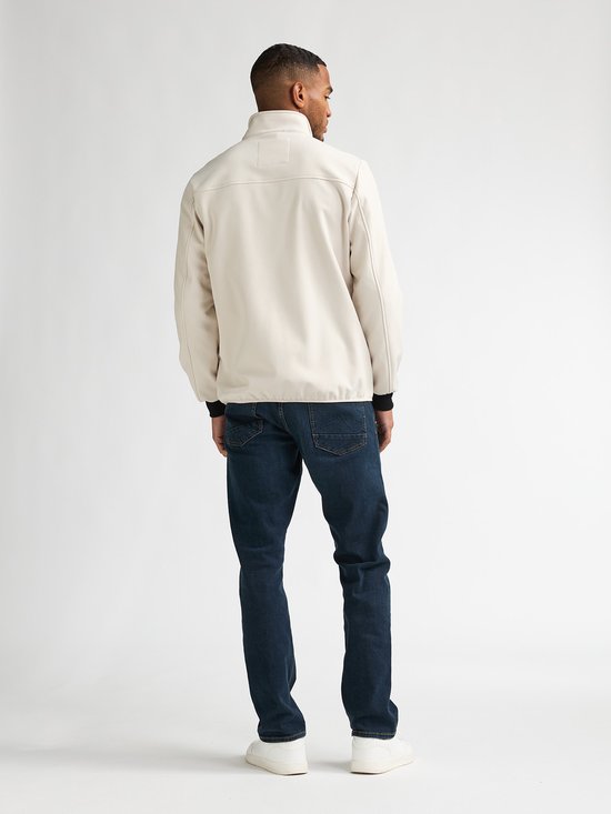 Man draagt een beige jas met jeans, van achteren gefotografeerd. De jas heeft beige mouwen en zwarte boorden.