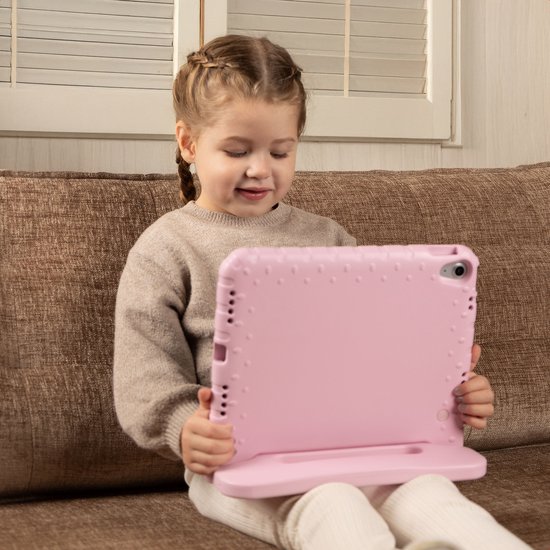 Kind zit op een bank en houdt een roze tablethoes met standaard vast.