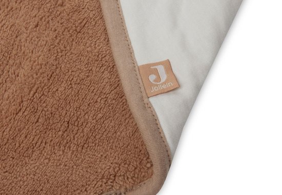 Détail d'une cape de bain blanc cassé avec intérieur marron en tissu éponge et bordure beige. Le logo Jollein est visible.