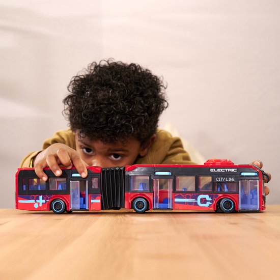Jongen raakt rode dubbele stadsbus aan. Bus met 'ELECTRIC CITY LINE', blauwe details en accordeonverbinding.
