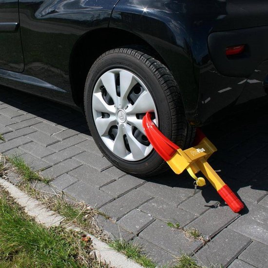 Gele wielklem met rode uiteinden, bevestigd aan een autoband op een oprit.