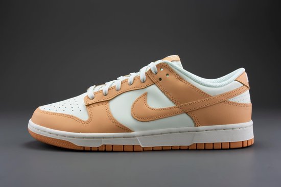 Nike Dunk Low damesschoen, wit met oranje overlays, op een grijze achtergrond.