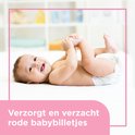 Lachende baby op zijn rug, benen omhoog houdend. Tekst: Verzorgt en verzacht rode babybilletjes.