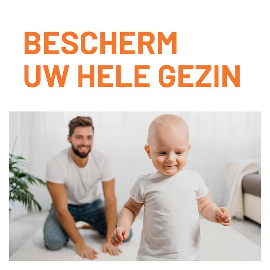 Een man speelt met zijn baby op een zacht tapijt, beide dragen witte kleding.
