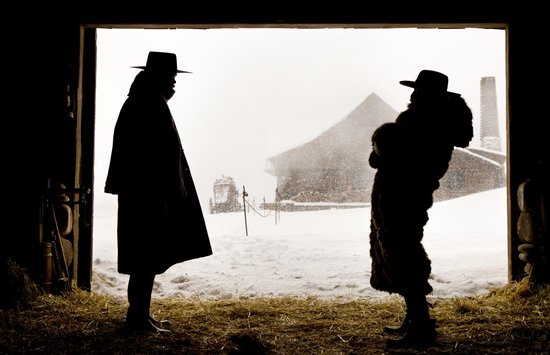 Twee silhouetten van mannen met hoeden in een deuropening, kijkend naar een besneeuwd landschap.
