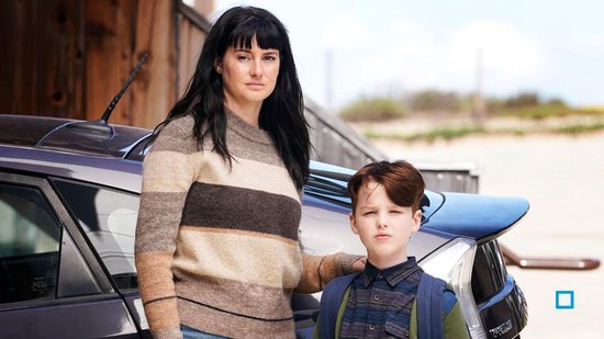 Een vrouw met zwart haar en een gestreepte trui staat naast een jongen met een rugzak, bij een auto.