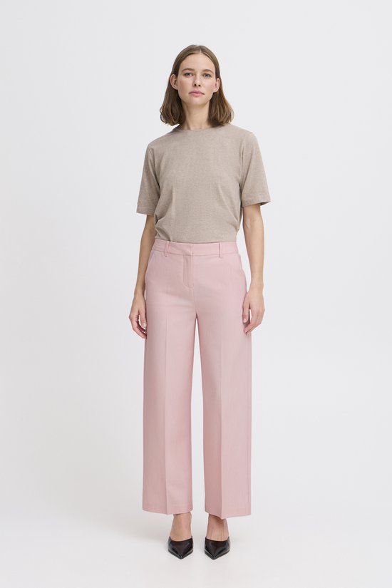Mannequin portant un pantalon large rose pâle et un t-shirt beige rayé.
