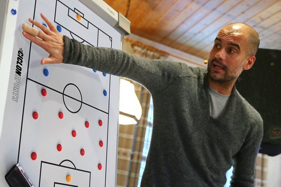 Entraîneur de football pointant vers un tableau tactique avec des joueurs bleus et rouges, avec le logo 'CICLON SPORTS'.