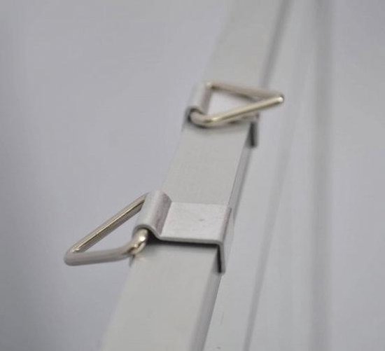 Gros plan sur des cintres triangulaires en métal argenté sur un tableau blanc.