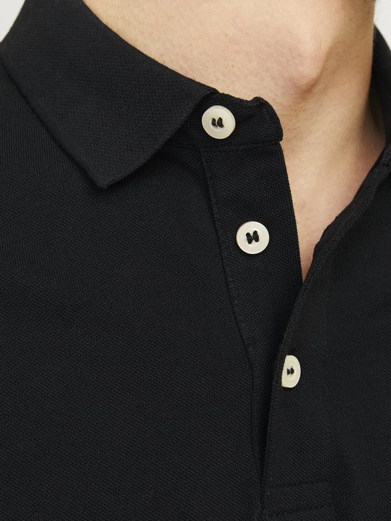 Close-up van de knopen van een zwart poloshirt.