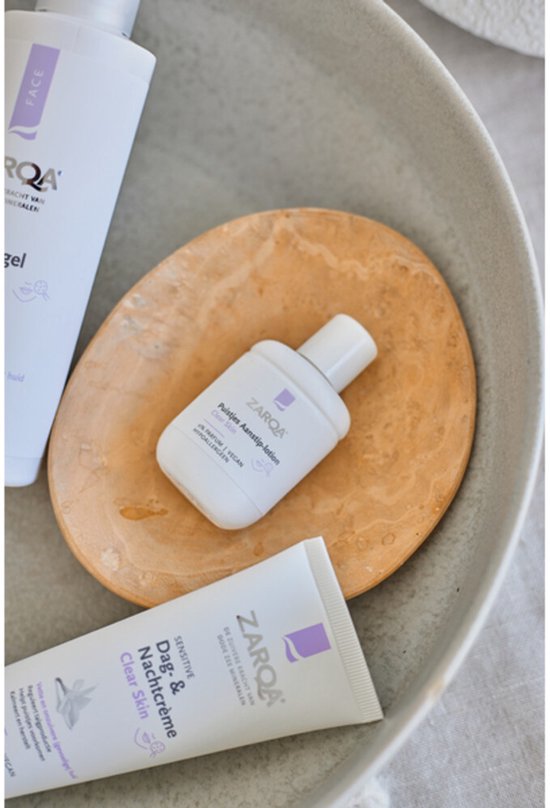 Een productpresentatie met Zarqa gezichtsverzorgingsproducten, waaronder een tube Dag- & Nachtcrème Clear Skin.