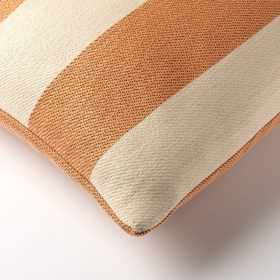 Detail van een crèmekleurig sierkussen met brede oranje strepen en biezen.