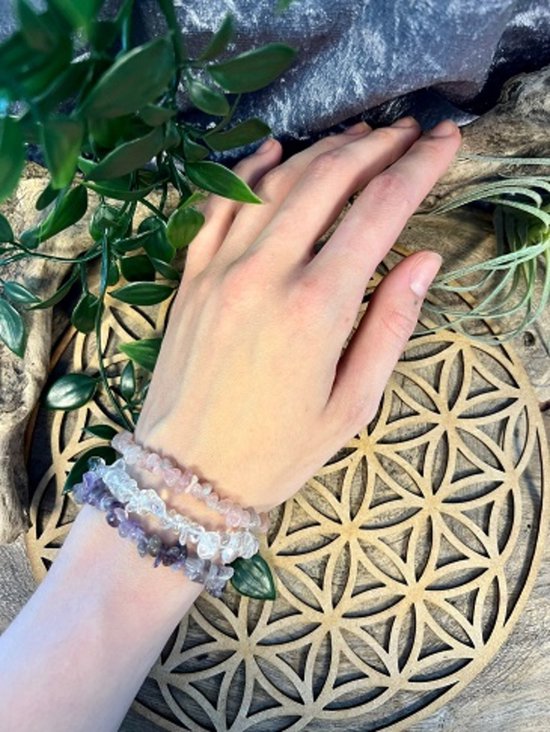 Hand met paarse, witte en roze armbanden met steentjes.