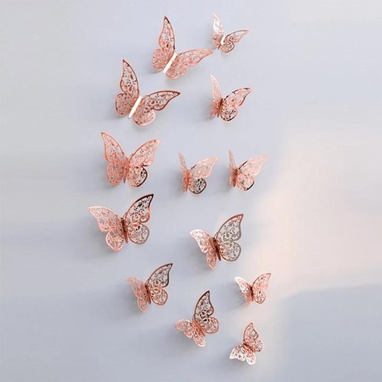 Twaalf 3D-vlinderstickers in roségoud met open, gedetailleerd ontwerp, bevestigd aan een lichte muur.
