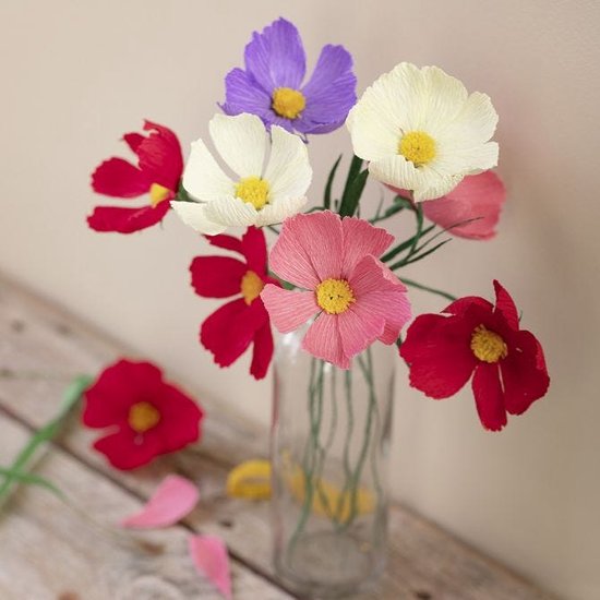 Boeket van zes gemaakte bloemen in de kleuren rood, roze, crèmekleur en paars, met gele kern, in een glazen vaas.