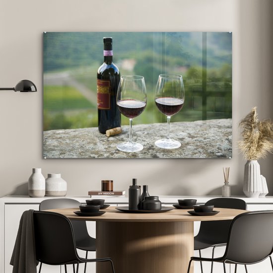 MuchoWow® Glasschilderij 120x80 cm - Schilderij acrylglas - Fles Rode wijn met wijngaarden van Sangiovese-druiven op achtergrond - Foto op glas - Schilderijen